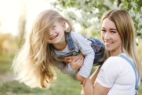 Joven madre con adorable hija en el parque con árbol de flores —  Fotos de Stock