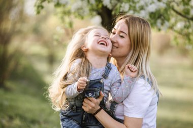 Genç anne ve güzel kızı parkta çiçek ağacıyla