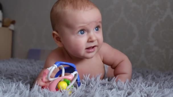Adorable grimacing funny baby in a diaper on all fours, standing on a plaid, looks at a gray background. — Stock Video