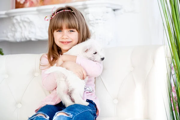 Child hugs a white terrier puppy — Stock Photo, Image