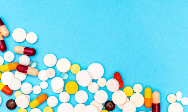 Different pills on blue background, top view and space for text