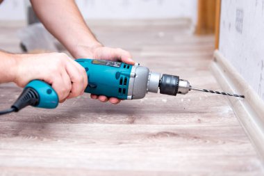 Adam süpürgeliği duvara sabitliyor.