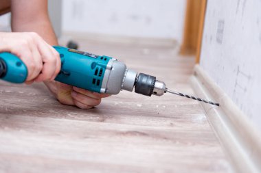 Adam süpürgeliği duvara sabitliyor.