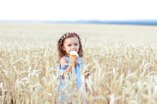 Meisje eet lekker brood in een tarweveld op een zomerdag. Oogstconcept — Stockfoto