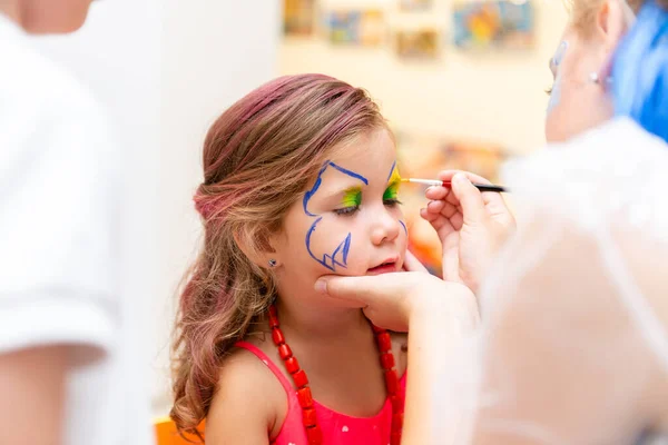 Une femme peignant un visage d'enfant à une fête d'enfants. visage de bébé — Photo