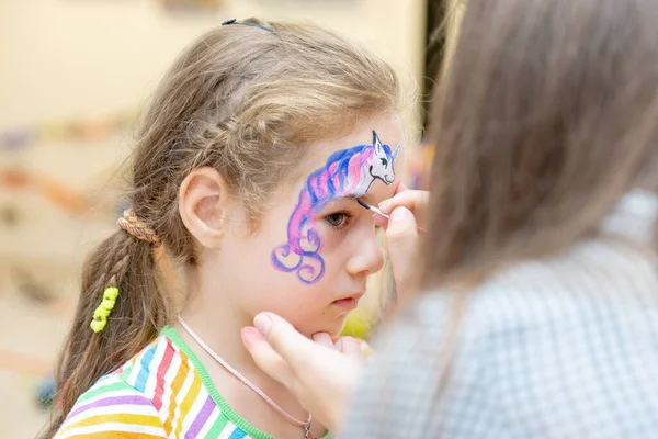Donna che dipinge una faccia da bambino a una festa per bambini. viso del bambino — Foto Stock