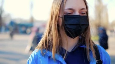 Avrupa 'da Coronavirus. Kız yol kenarında koruyucu bir tıbbi maske takıyor..