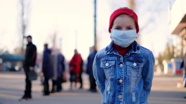 Petite fille dans la rue près de la route dans un masque de protection — Video