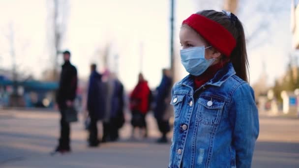 Petite fille dans la rue près de la route dans un masque de protection — Video