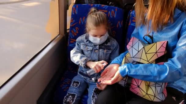 Коронавирус в Европе. Дезинфекция рук в общественном транспорте. Мать с ребенком в автобусе — стоковое видео