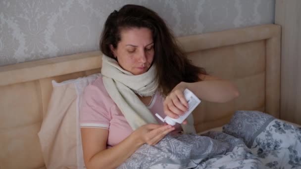 Vrouw voelt zich ziek liggend in bed en pillen drinken. — Stockvideo