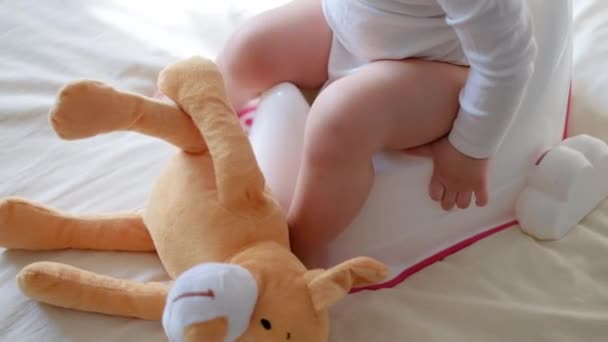 Babybeine hängen an einem Topf. Der Junge sitzt auf dem Töpfchen. Lustiges Baby sitzt auf dem Morgentopf im Schlafzimmer — Stockvideo