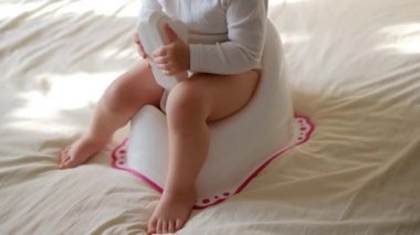 Tencerede sallanan bebek bacakları. Çocuk lazımlığın üzerinde oturuyor. Yatak odasındaki sabah tenceresinde oturan komik bebek.