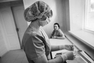Hastanede maske takan genç bir hastaya şırınga enjekte eden kadın bir doktor. Tıbbi sağlık hizmeti kavramı.