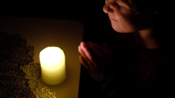 Niño triste a la luz de las velas, chico de oración en la noche, retrato pensativo de un niño molesto, cara — Vídeo de stock