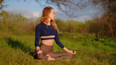 İnce kız gün batımında parkta yoga yapıyor. Açık hava sağlık hizmetleri. Yan görünüm
