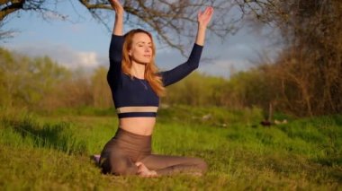 İnce kız gün batımında parkta yoga yapıyor. Açık hava sağlık hizmetleri. Yan görünüm