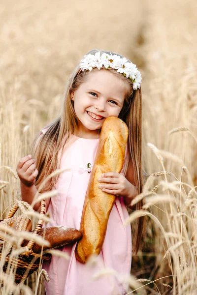 Щаслива маленька дівчинка дитина в пшеничному полі влітку. Діти з хлібом. Маленька дівчинка в зерновому полі. Дівчинка на полі пшениці з хлібом — стокове фото