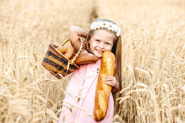Gelukkige kleine meisje kind in tarwe graanveld in de zomer. Kinderen met brood. Klein meisje in het graanveld. Meisje op het veld van tarwe met brood — Stockfoto