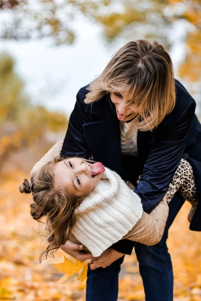 Mãe e filha se divertindo juntas, segurando folhas de outono, maternidade — Fotografia de Stock