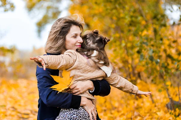 Мать и дочь веселятся вместе, держат осенние листья, материнство — стоковое фото