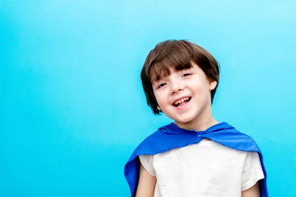 Boy en el cabo superhéroe sonriendo sobre el fondo del cielo, feliz infancia. — Foto de Stock