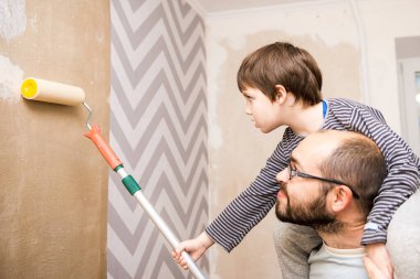 Neşeli baba ve oğul birlikte duvar kağıdı asıyor, ev tadilatı, eğlence