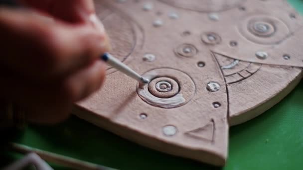 Uma jovem pinta um artesanato de barro ou prato com tintas. Close-up — Vídeo de Stock