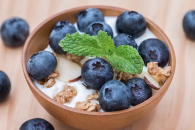 Granola ve ahşap kase organik yaban mersini ile yoğurt.