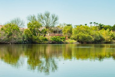 Ağaçlar ve gölde yansıtan evleri.