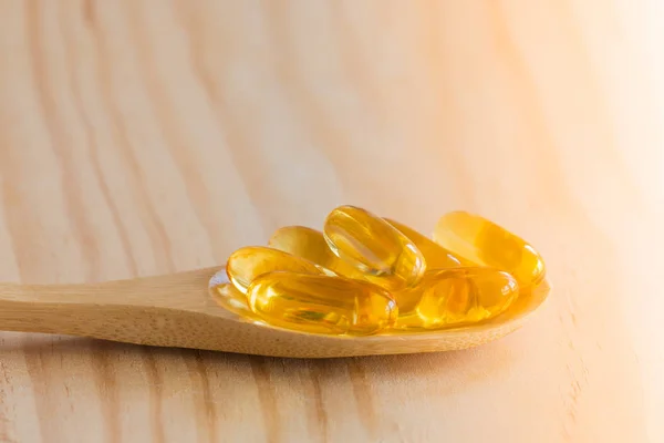 Fish oil, omega 3 with vitamin D capsules in spoon.