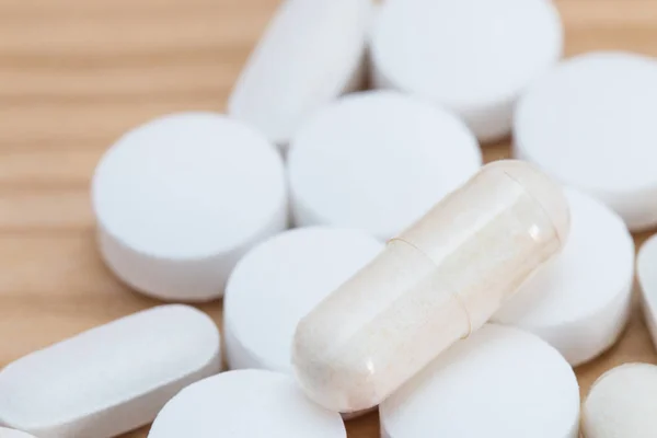 Cápsulas de medicina blanca y tabletas blancas sobre fondo de madera — Foto de Stock