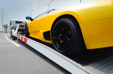 Düz yatak çekici platformu aşağı sıkıntısı çeken kırık bir araç. Yol kenarı Servisi