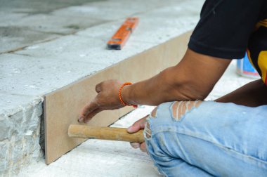 Tiler, yapıştırıcının üzerine porselen döşeme yerleştiriyor. Döşeme döşemesi