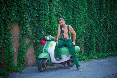 Jartiyer yakışıklı bir adam bir scooter üzerinde oturur