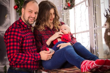 Kışın pencere kenarında oturan genç bir çocuk ile genç aile