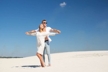 Sevgi dolu bir çift el ele tutuşarak sıcak güneşin beyaz kumları arasında bir yüz hazır