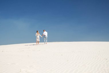 Beyaz elbiseli güzel bir kız onu adam kum izler