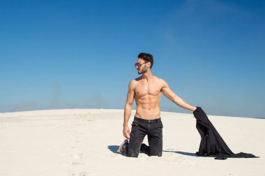 Yakışıklı bir erkek gömleği kum üzerinde kapalı alır