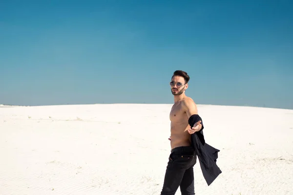 Een knappe brunette jongen met een naakte torso strekt zich uit zijn hand — Stockfoto