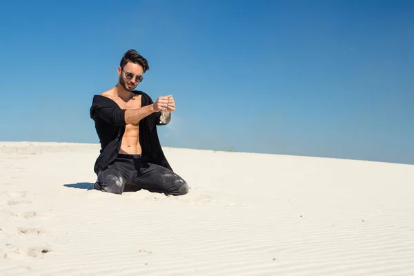 A guy kneeling sand white sand — Stock Photo, Image