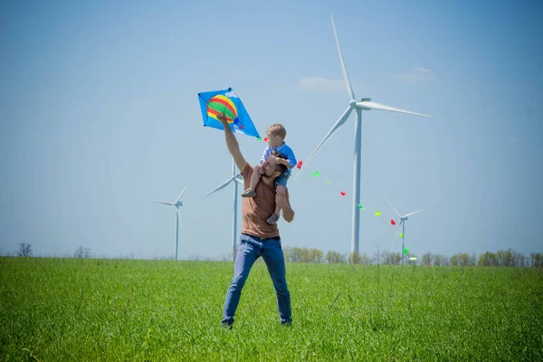 Baba ve çocuk bir uçurtma rüzgar jeneratörleri yakınlarında denize indirmek