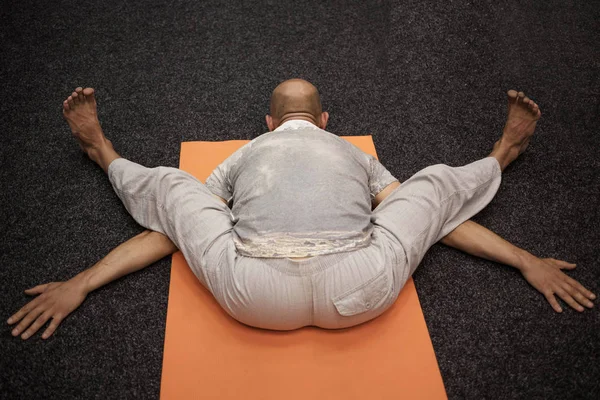 A man in bright clothes on an orange yoga mat — Stock Photo, Image