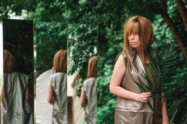 Bir hurma dalı onun elinde bir kızla dikkatle Aynaya bakar