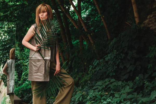 Kalın yeşil ağaçlık bir ayna ile bir kız