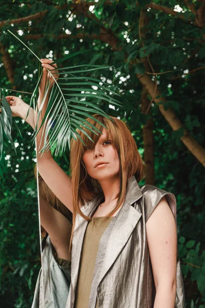 Bir kız bir ayna onun elinde fern şubesi ile eğilerek standları