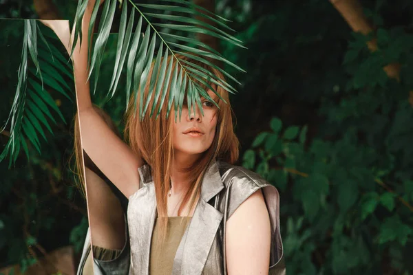 Şehvetli bir görünüme sahip güzel bir kız bir fern şube gözleriyle koruyor