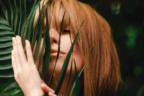 Kız yavaşça fern şube onun yüzüne okşar.