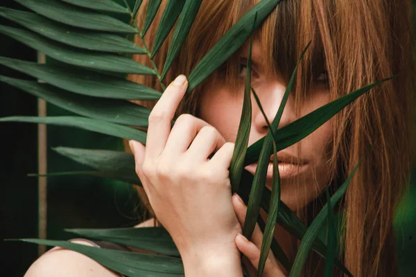 İnanılmaz güzel kız yüzünü bir hurma dalı ile kapsar