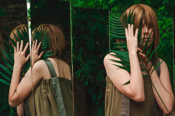 En flicka som håller en gren av en ormbunke mellan hennes handflator — Stockfoto